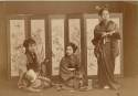 Three girls sitting or standing before a painted screen - Japan